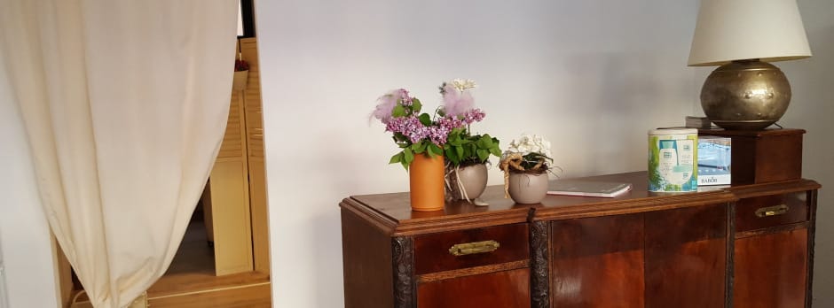Behandlungsraum mit antikem Sideboard, frischen Blumen und Pflegeprodukten